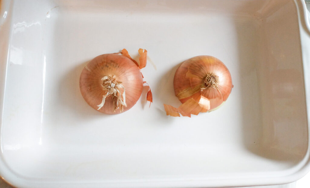 onion cut in half and placed side by side in baking dish