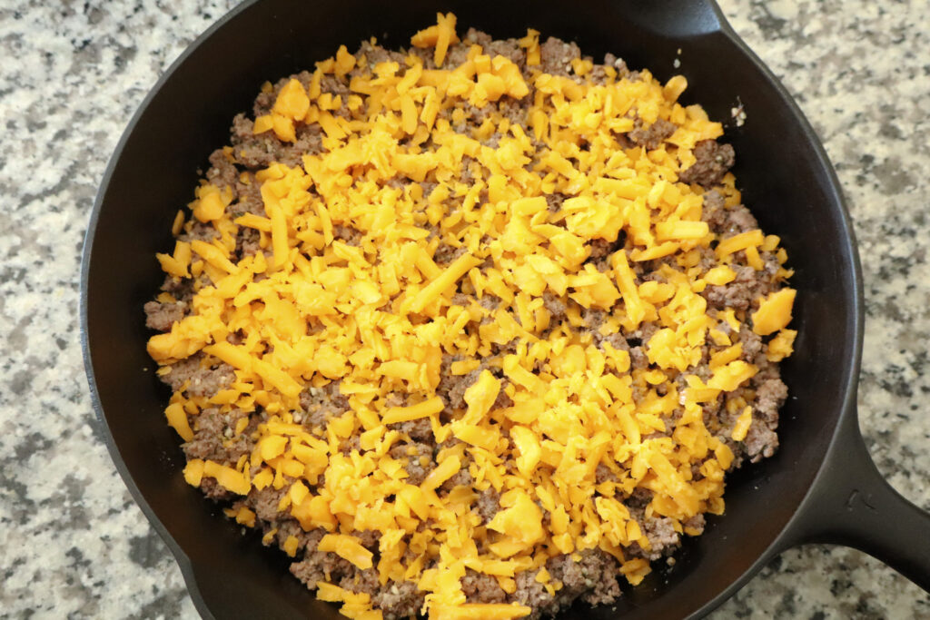 ground beef if cast iron with cheddar cheese on top