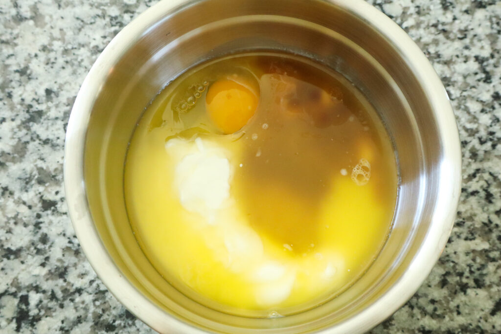 wet ingredients for honey cupcakes in stainless steel mixing bowl