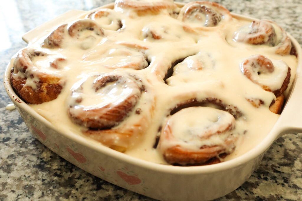 cinnamon rolls with cream cheese topping in baking dish