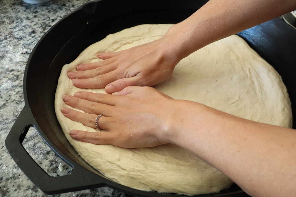 pressing the dough to fit in cast iron pan