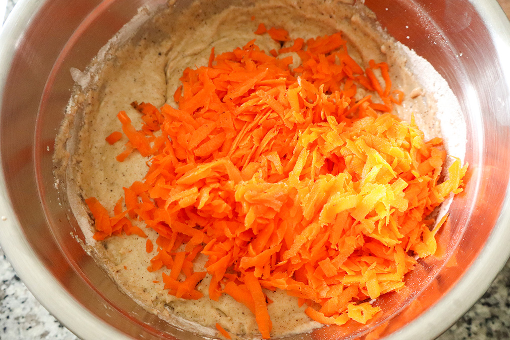 shredded carrots being added to cake batter