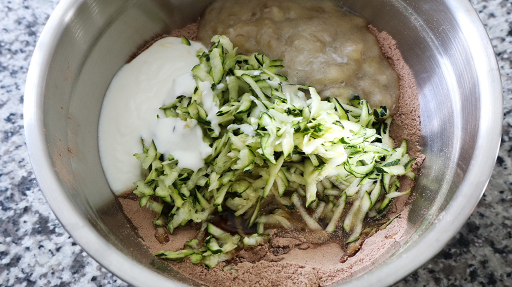 mashed banana, grated zucchini and yogurt being added to dry ingredients